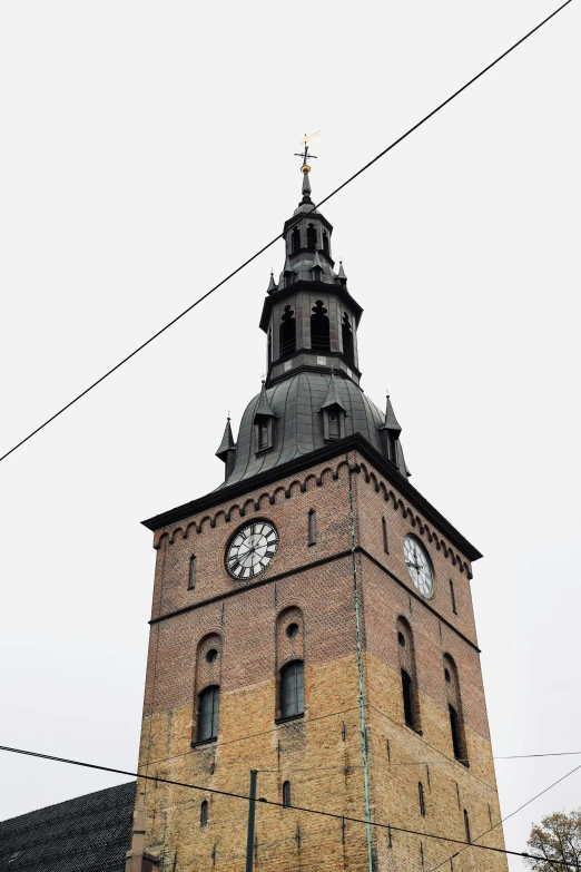 a brick clock tower sitting below power lines
