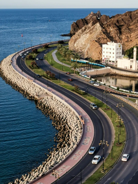 a car driving along a sea - side road past an island