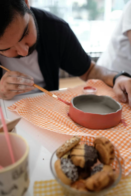 a man sitting at a table writing on paper next to a pie