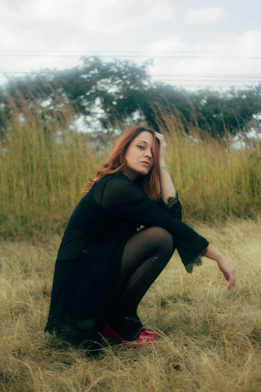 the woman is kneeling in a field of tall grass