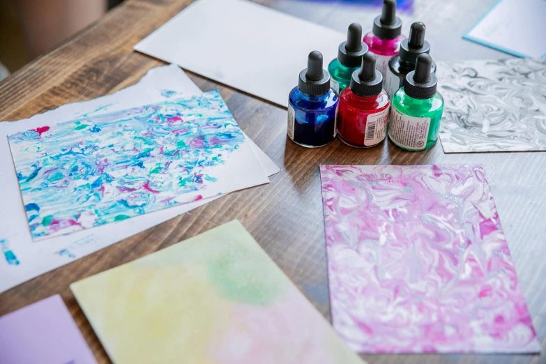 a table with some colorful papers and a few bottles of ink