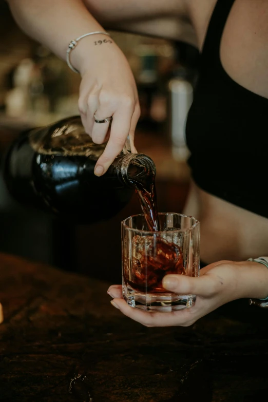 a person pouring a beverage into a glass