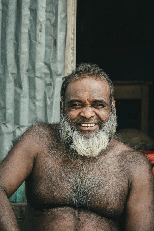 a man with white beard standing by a building