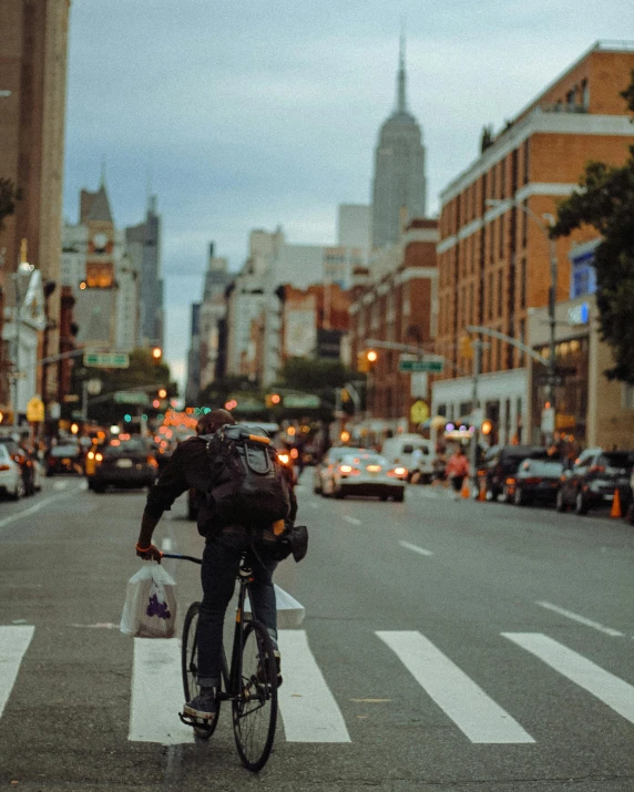 a bicyclist with a large back pack is riding across the street