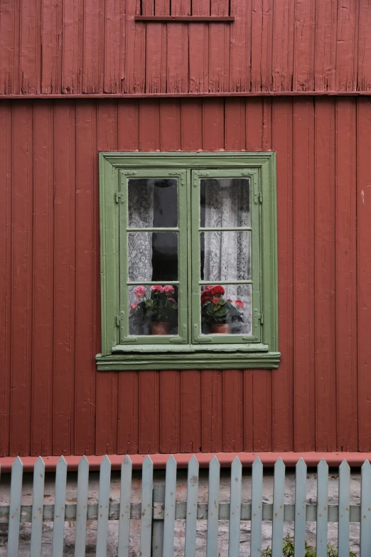 a red barn with a green window with flowers