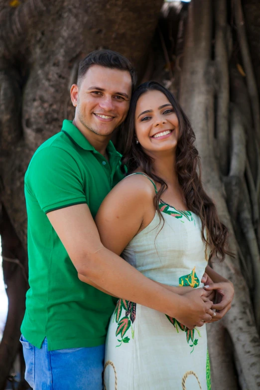 a man and woman smiling next to a tree