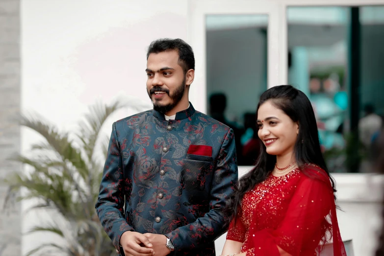 a woman in red dress stands beside a man