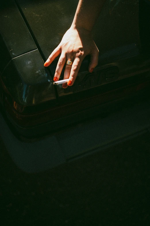 a person with red nails touches a cigarette