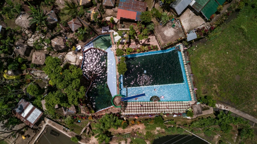 aerial view of an overhead s of an outdoor pool surrounded by jungle