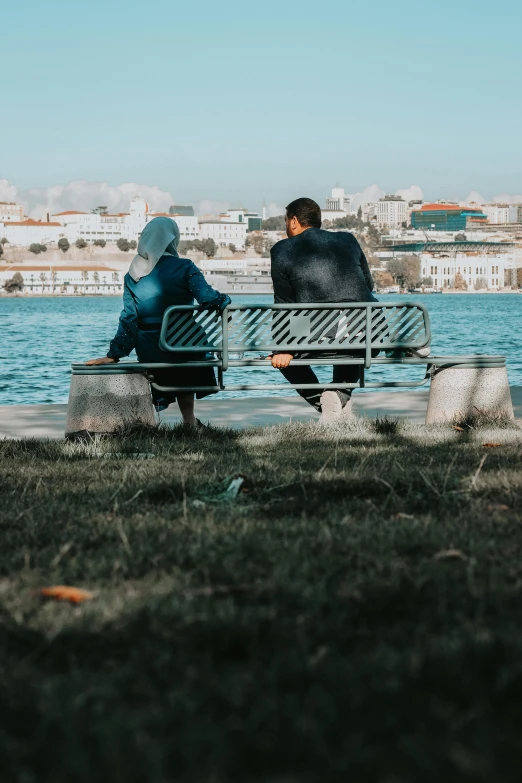 two people sit on a bench overlooking a body of water