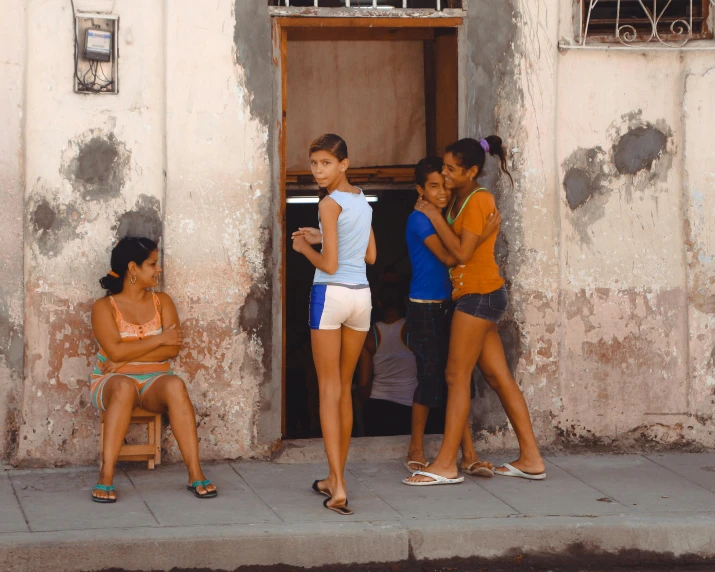 four people standing outside a rundown building on the street