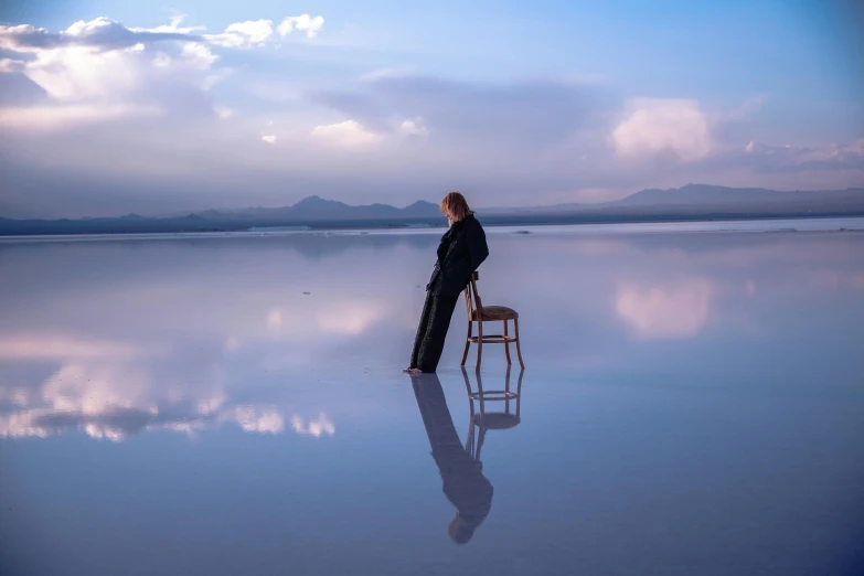 a man standing on a beach near a chair