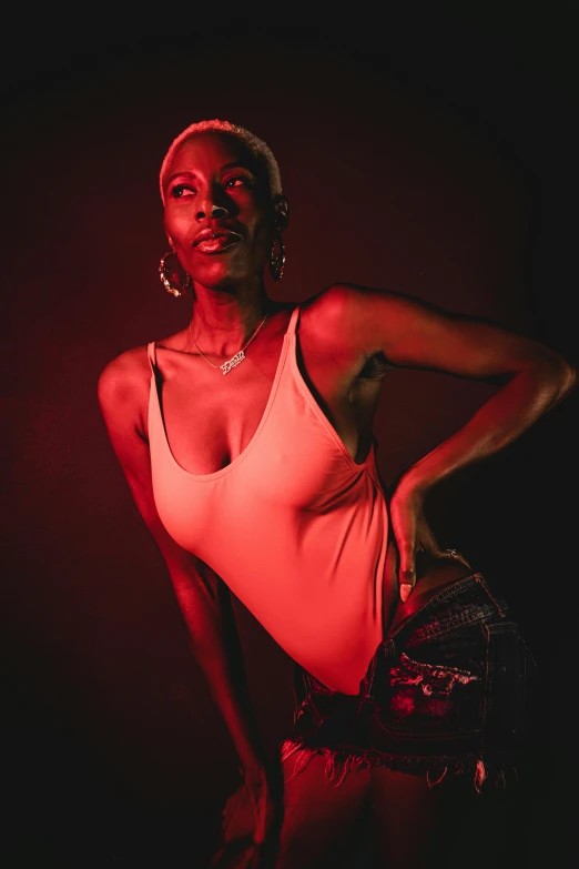 a woman wearing a white top standing against a dark background