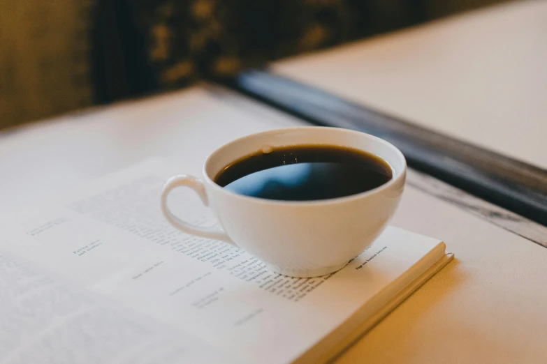 the book is next to the coffee cup