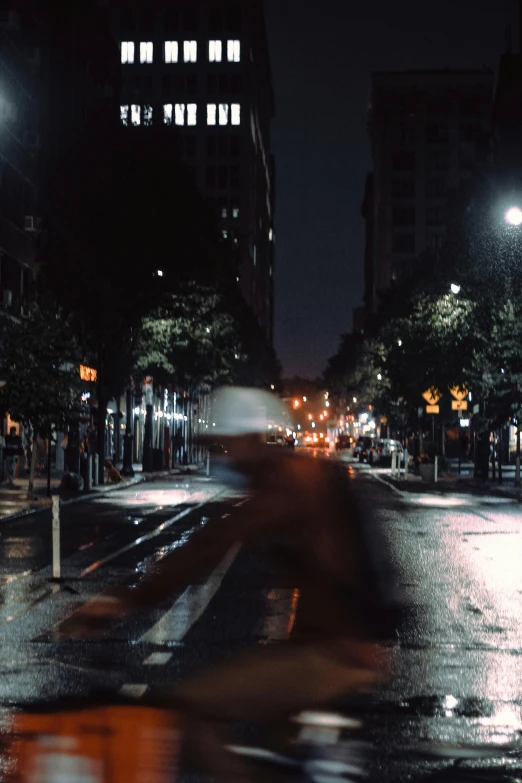 a blurry bike rider in the dark on a wet night