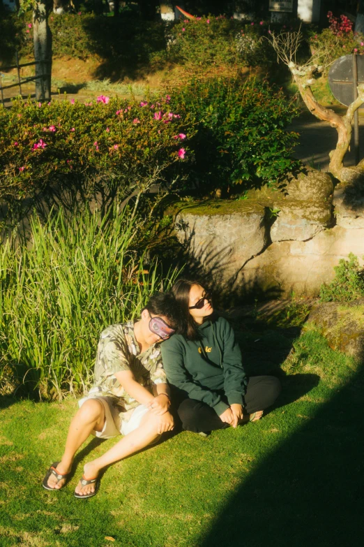 two people lying in the grass near some bushes