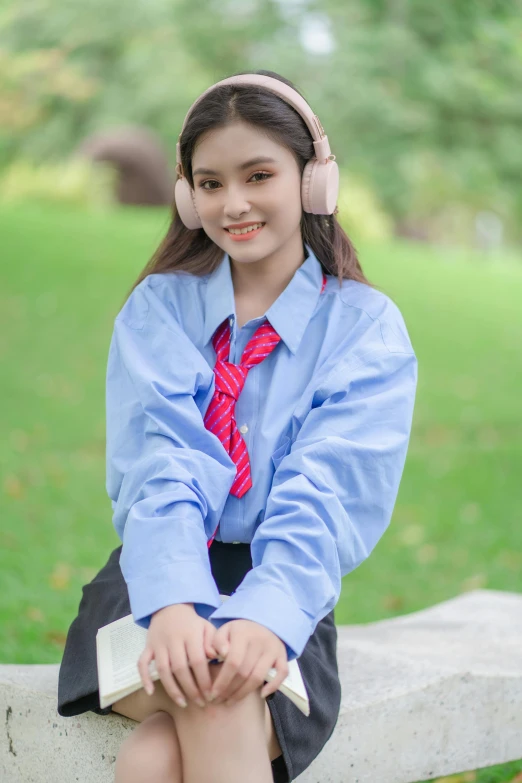 a girl sitting on a fence wearing headphones and blue shirt