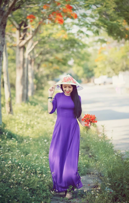 a woman is holding her hat in the grass