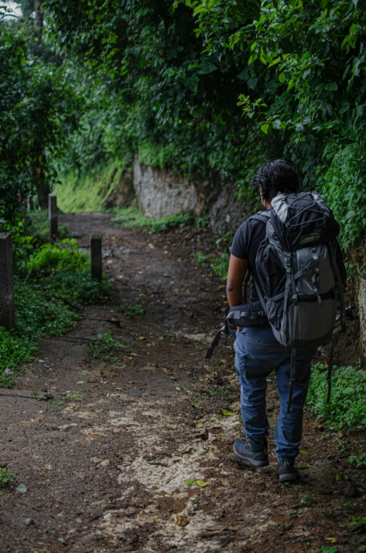 a person walking up a dirt path wearing a backpack