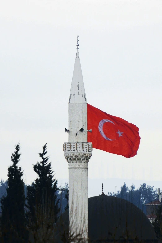 the two flags fly by each other near a steeple