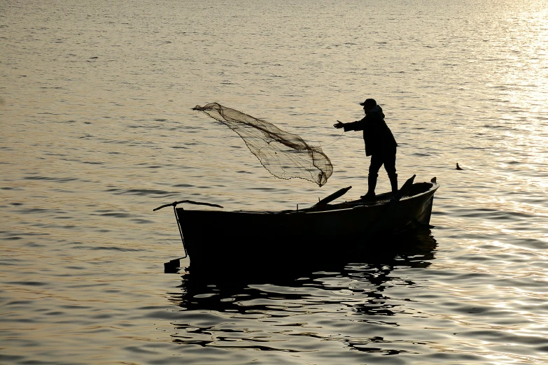 a man standing in the end of a boat throwing soing