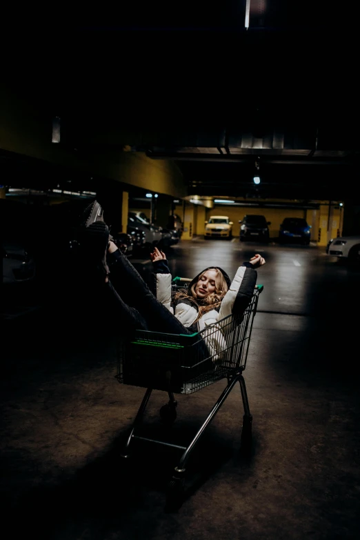 a person laying in an empty shopping cart with one hand up