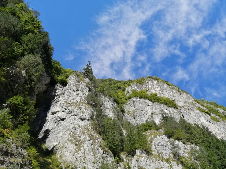 large rocky outcropping of tree line under cloudy blue sky