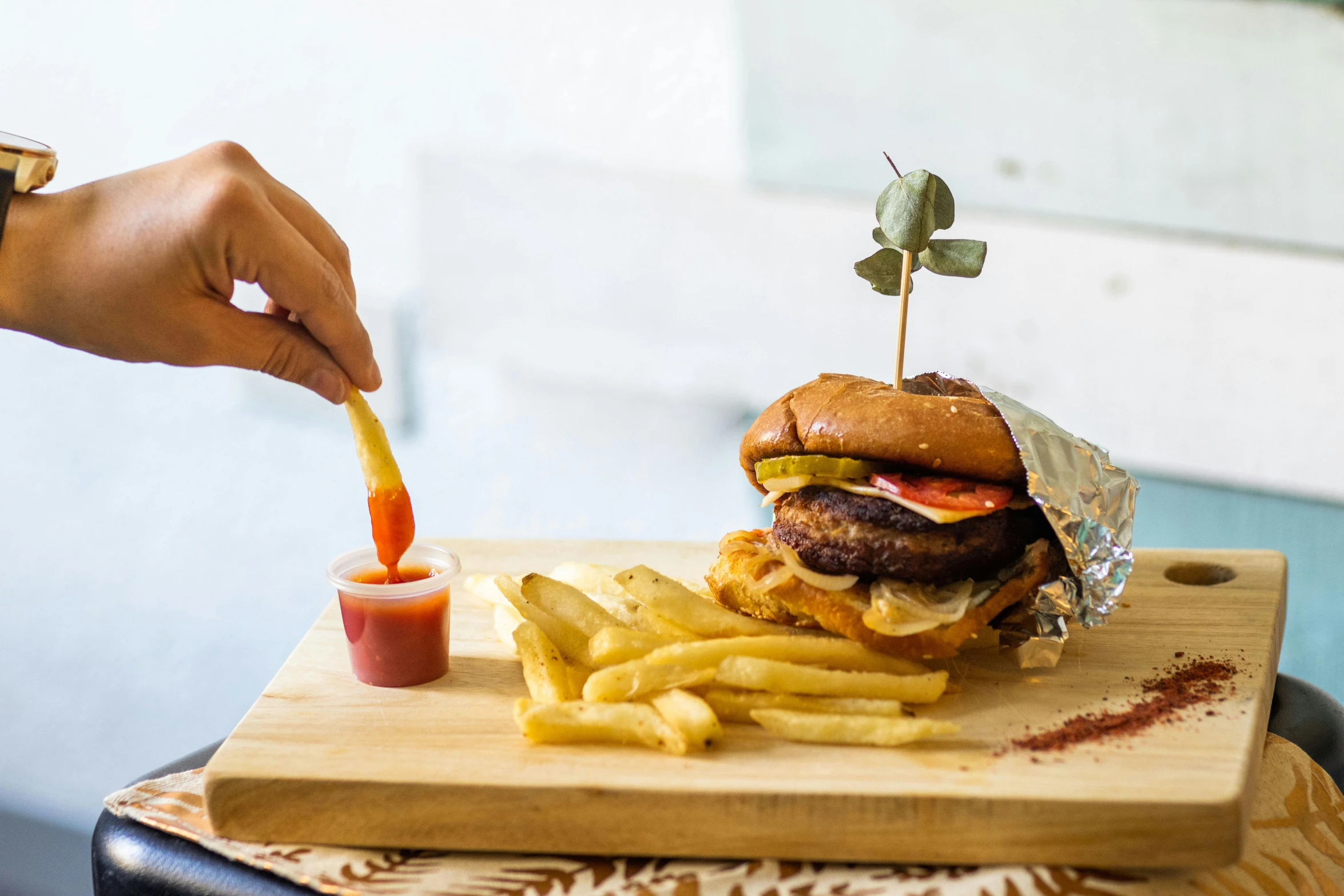 someone is eating a hamburger with fries on the table