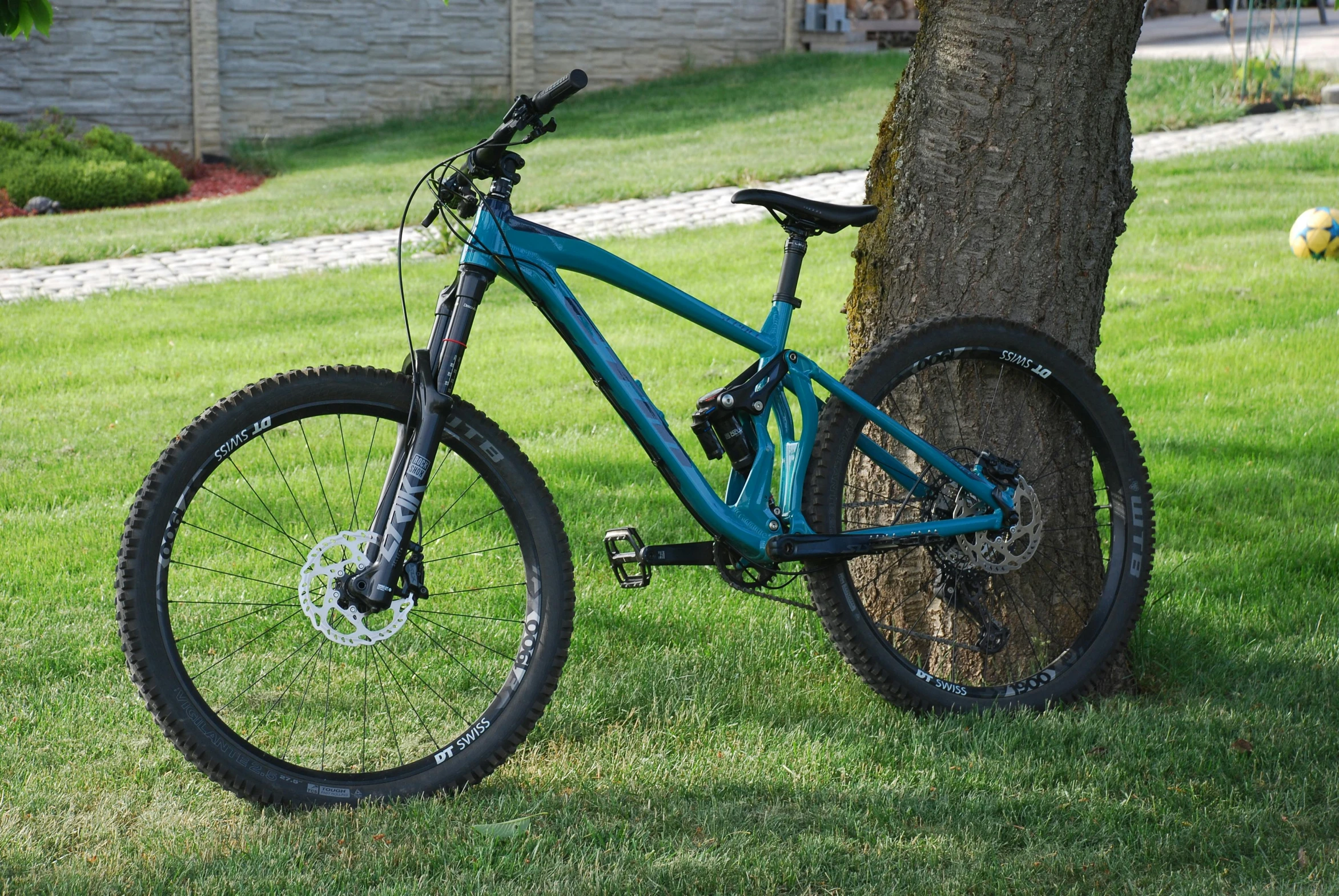 a blue mountain bike parked next to a tree