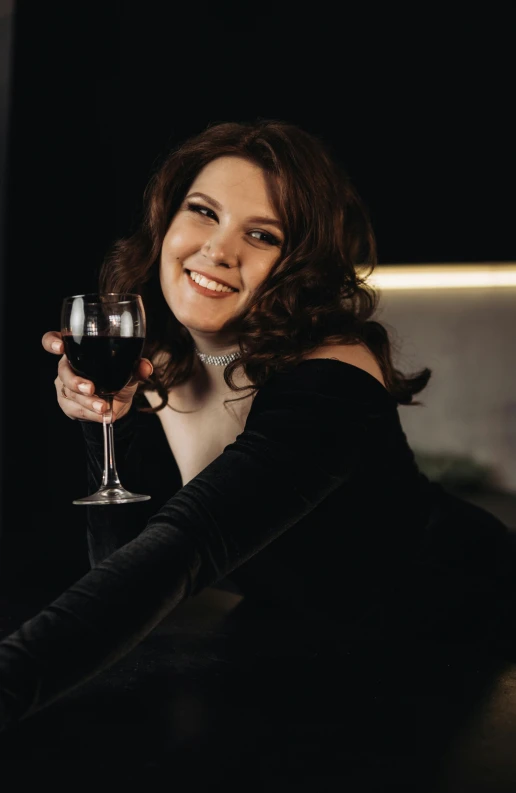 a woman posing with a glass of wine in her hand