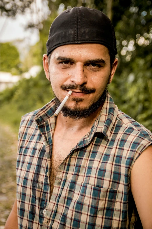 a man standing in the middle of a forest holding a cigarette