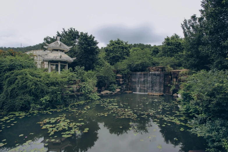 a pond and gazebo with trees in the background