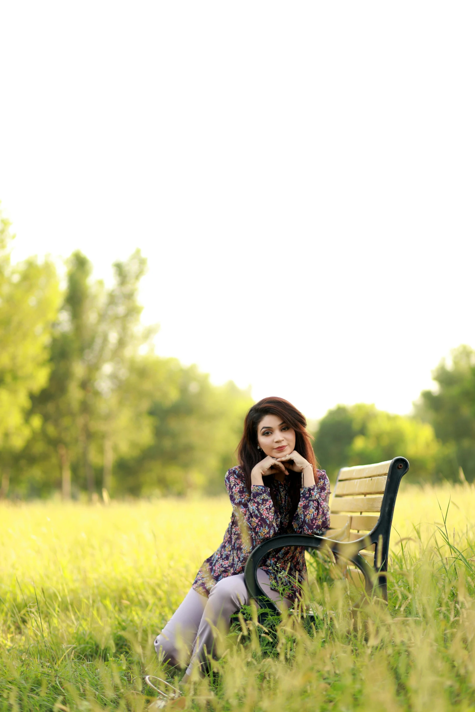 a  sitting on a bench in tall grass