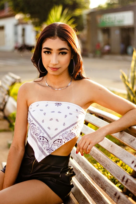 a very beautiful young lady posing on a bench