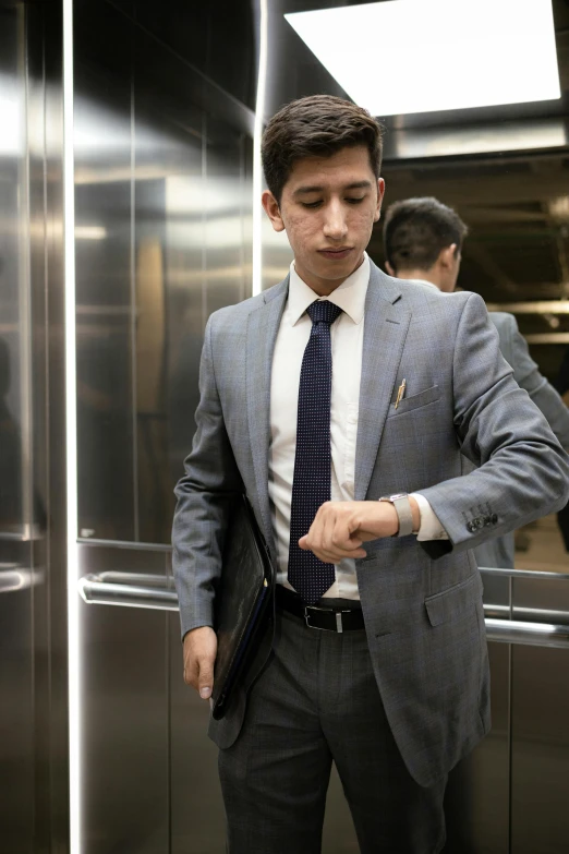 young man in a suit using his hand held out to touch his wrist