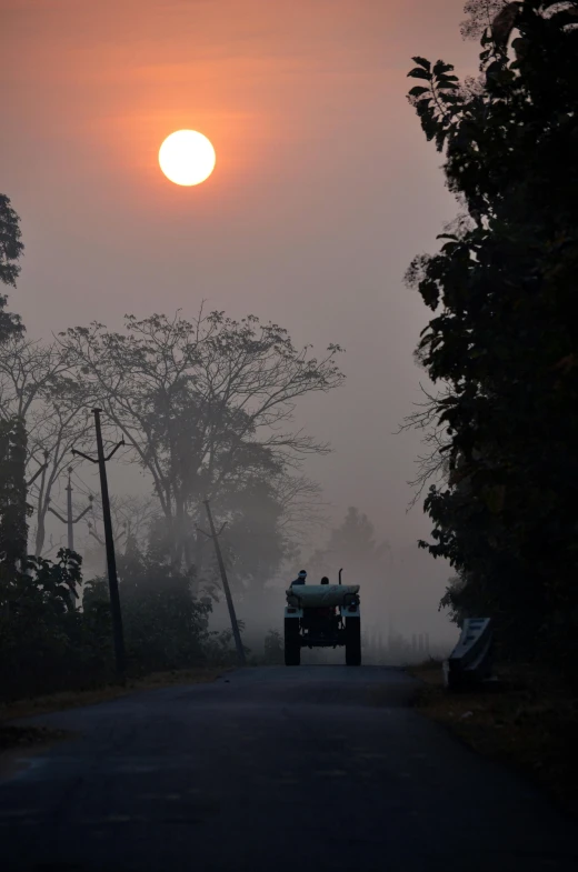 a truck driving down a road under a sun