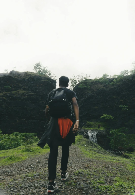 a man walking uphill carrying a backpack on his back