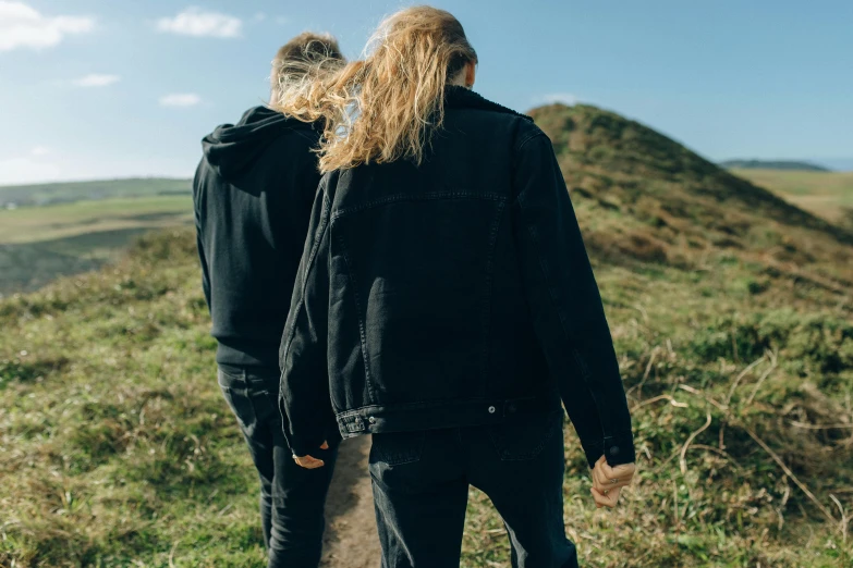 the two people are walking up a hill together