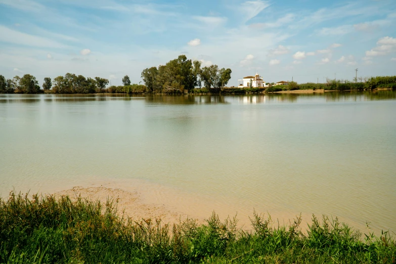 a lake and a house are seen near a bank