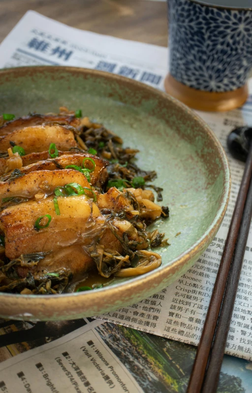 a bowl filled with chicken and green vegetables on top of a wooden table