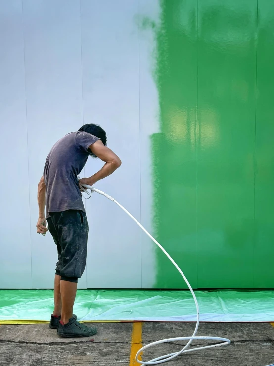 a man in a blue shirt is pumping water onto a white hose