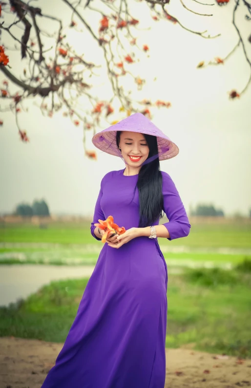 a woman in a purple dress and hat is holding oranges