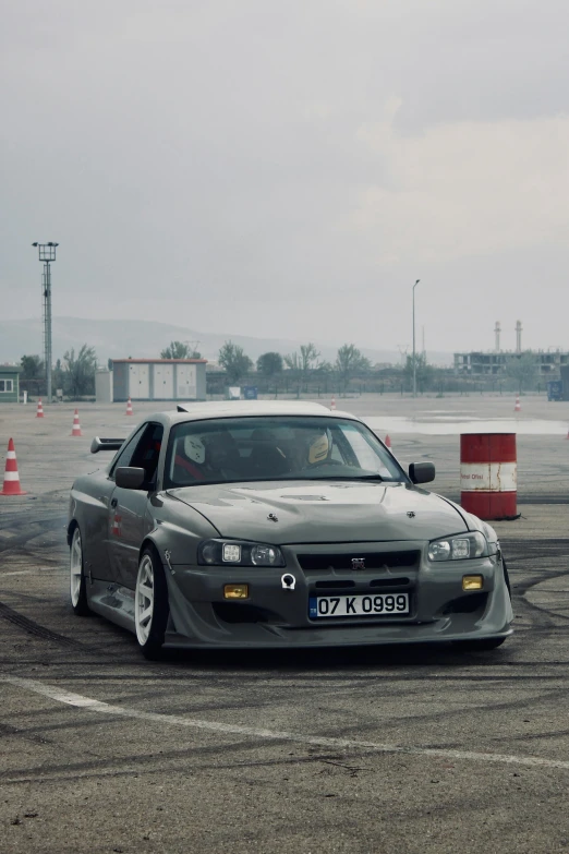 a grey car on a racetrack in front of cones