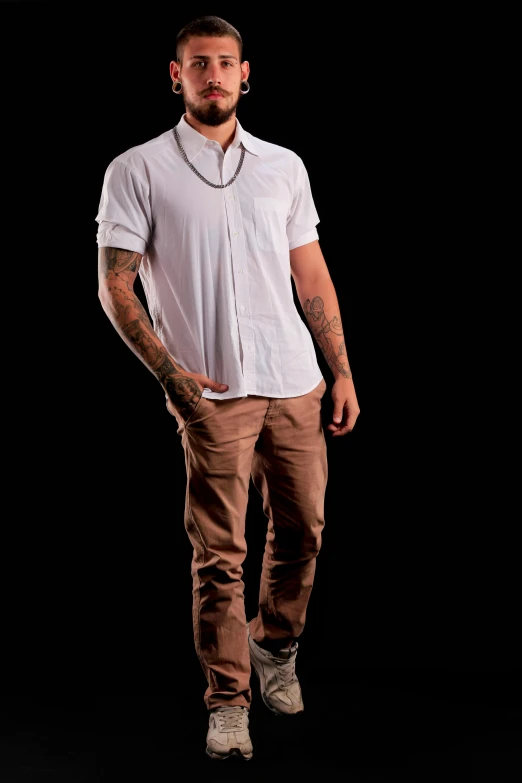 a man in a shirt and brown pants poses for the camera