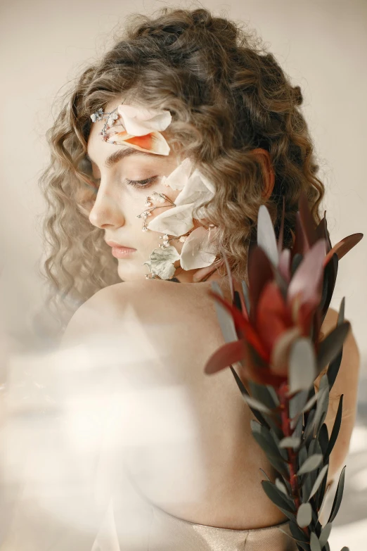 a  holding an arrangement of plants next to her face