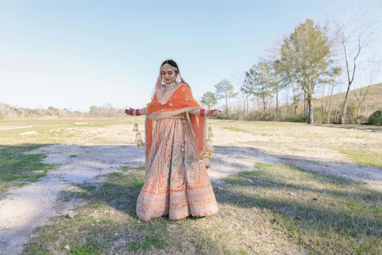 a woman standing in a field wearing an orange dress