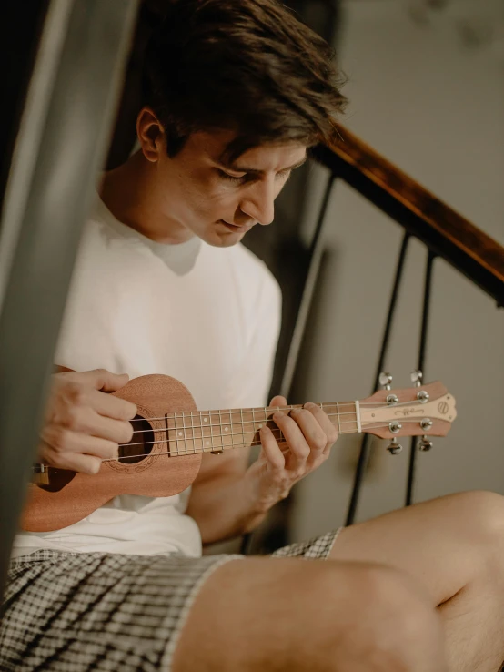a young man playing an ukulele at his home