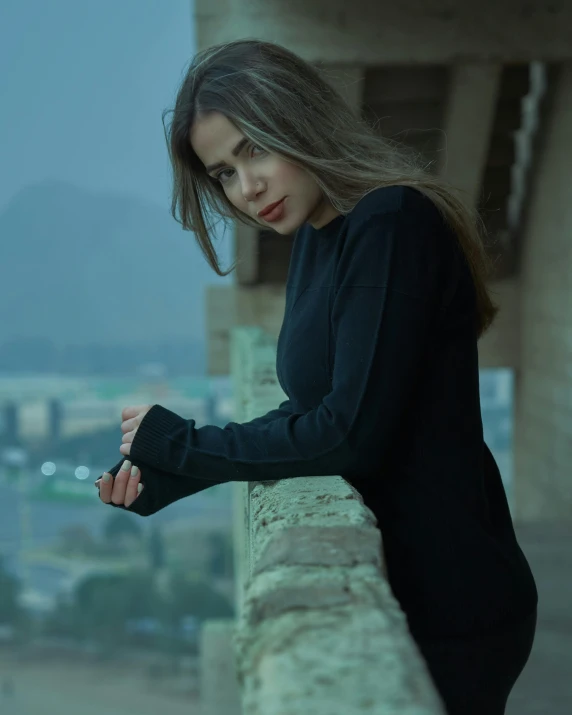 a woman in black leaning on a ledge