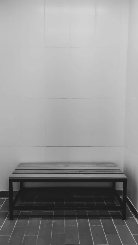 a long bench is in the corner of a tile floor