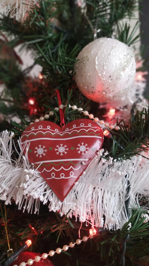 a red christmas decoration heart ornament on a tree